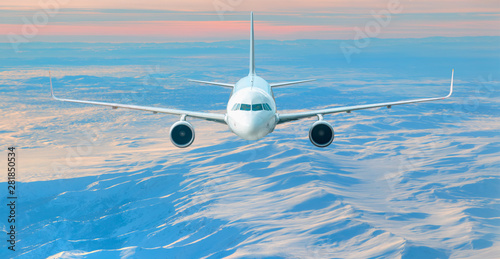 Airplane is flying over low clouds and snowy mountains