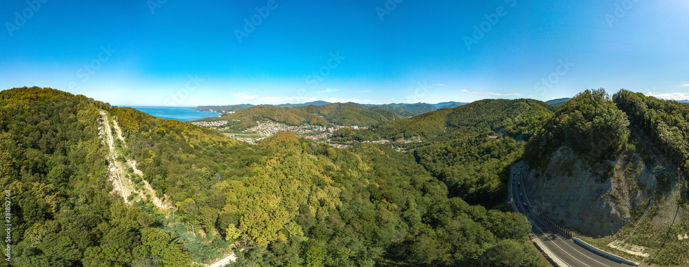 drone aerial view - summer cloudless day over a mountain pass. Narrow winding seaside road among wooded mountains.