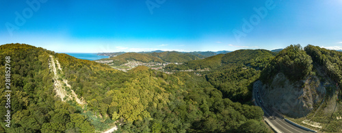 drone aerial view - summer cloudless day over a mountain pass. Narrow winding seaside road among wooded mountains.