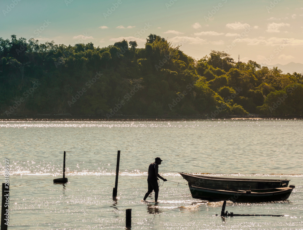 Fisherman pulling his boat on the shallow beach