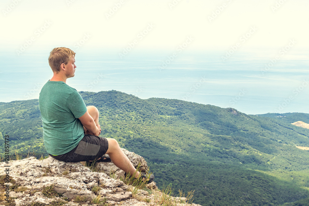 Naklejka premium Young man practicing yoga pose sitting on the rocky peak. Man do meditation and enjoying view