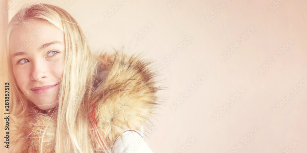 portrait of a young girl blonde with long hair in a warm coat with a fur hood on the street looks into the distance with a smile and sadness portrait of a young girl blonde with long hair in a warm coat with a fur hood on the street looks into the distance with a smile and sadness