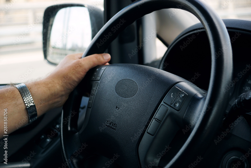men's hand holding the steering wheel of a business class car - image 