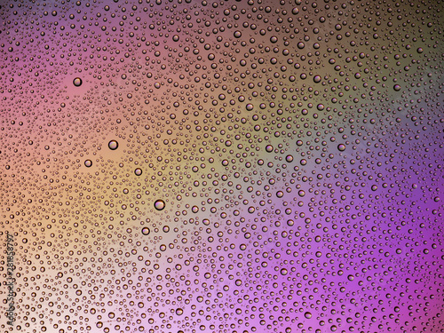 Water droplets on the glass with a colored background. Drops of water.