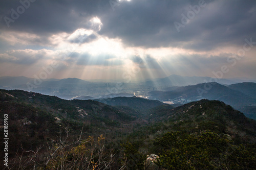 산 위에서 보는 구름 사이로 쏟아지는 햇빛 the sunlight pouring through the clouds seen above the mountain.