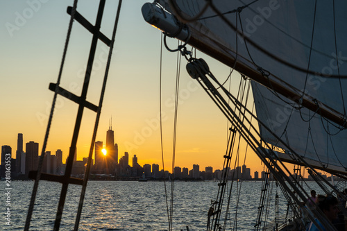 Chicago sunset with sunburst from deck of schooner with sails, rigging, and boom in foreground