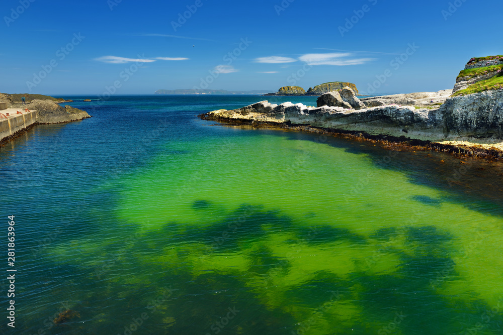Vivid emerald-green water at Ballintoy harbour along the Causeway Coast in County Antrim. Rugged coast of Northern Ireland.