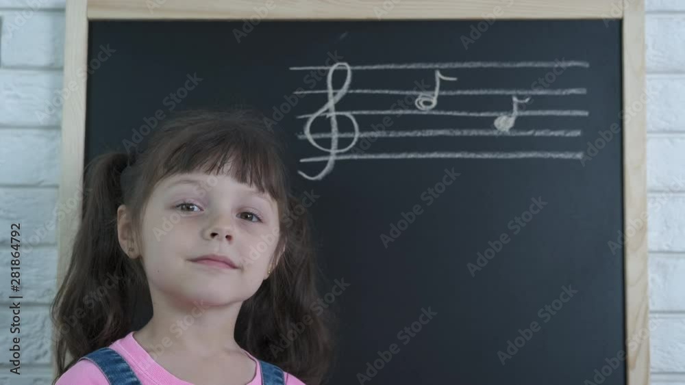 Music on blackboard. Cute little girl at the school chalkboard with written musical notes. Music on blackboard. Cute little girl at the school chalkboard with written musical notes.