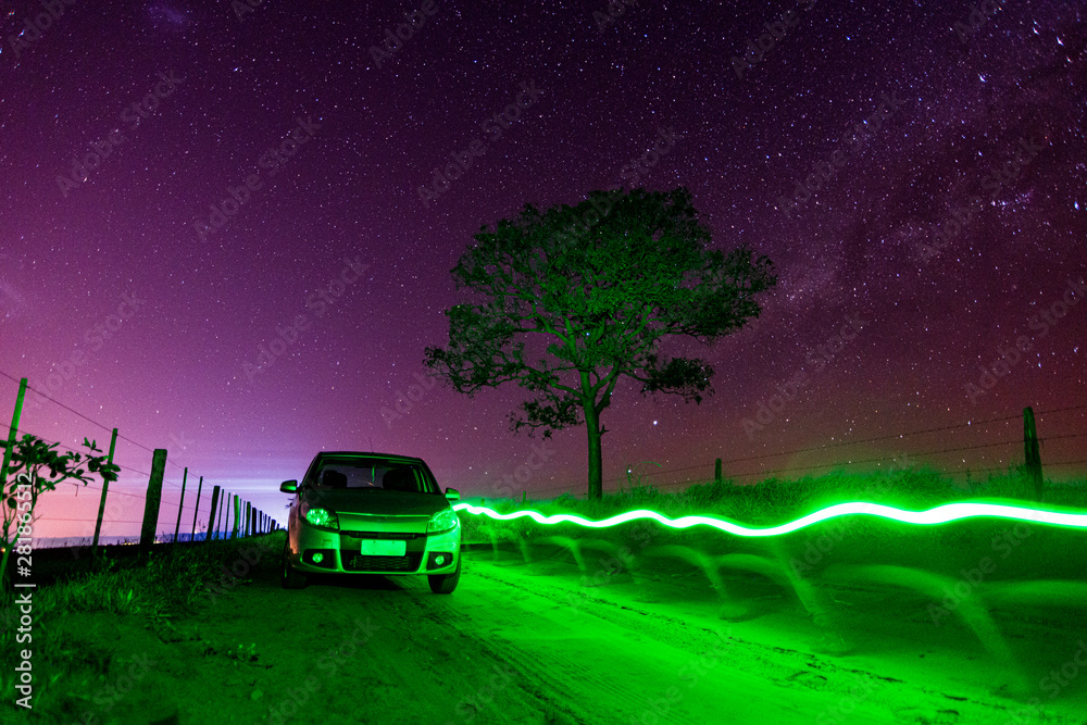 Drawing with green light over dirt road with parked car and starry sky. Drawing with green light over dirt road with parked car and starry sky.