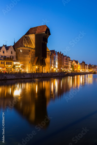 Scenic view of the lit Crane and other old buildings along the Long Bridge waterfront at the Main Town in Gdansk, Poland, in the evening.