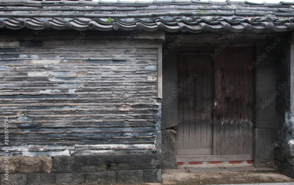 A wooden door is built into a roofed wall made of mud and tiles surrounding part of a temple in Tokyo’s nostalgic Yanaka district, Japan. A wooden door is built into a roofed wall made of mud and tiles surrounding part of a temple in Tokyo’s nostalgic Yanaka district, Japan.
