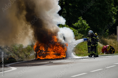 France road, July 22, 2014. Firefighters putting out a fire from a burning car