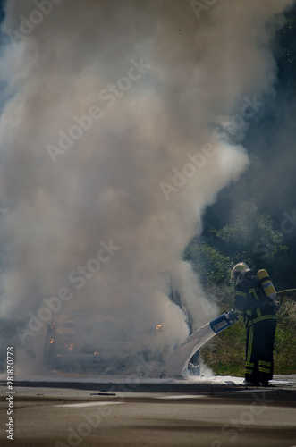 France road, July 22, 2014. Fireman putting out a car fire between smoke and flames