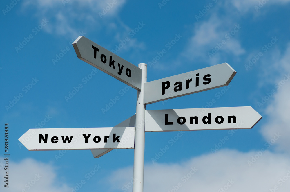 Closeup of destination panels with different cities for holidays on cloudy sky background Closeup of destination panels with different cities for holidays on cloudy sky background