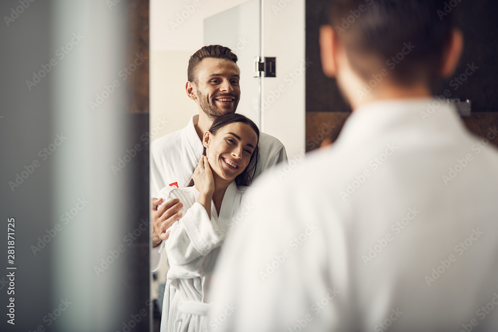 Loving couple in white bathrobes standing in the bathroom Loving couple in white bathrobes standing in the bathroom