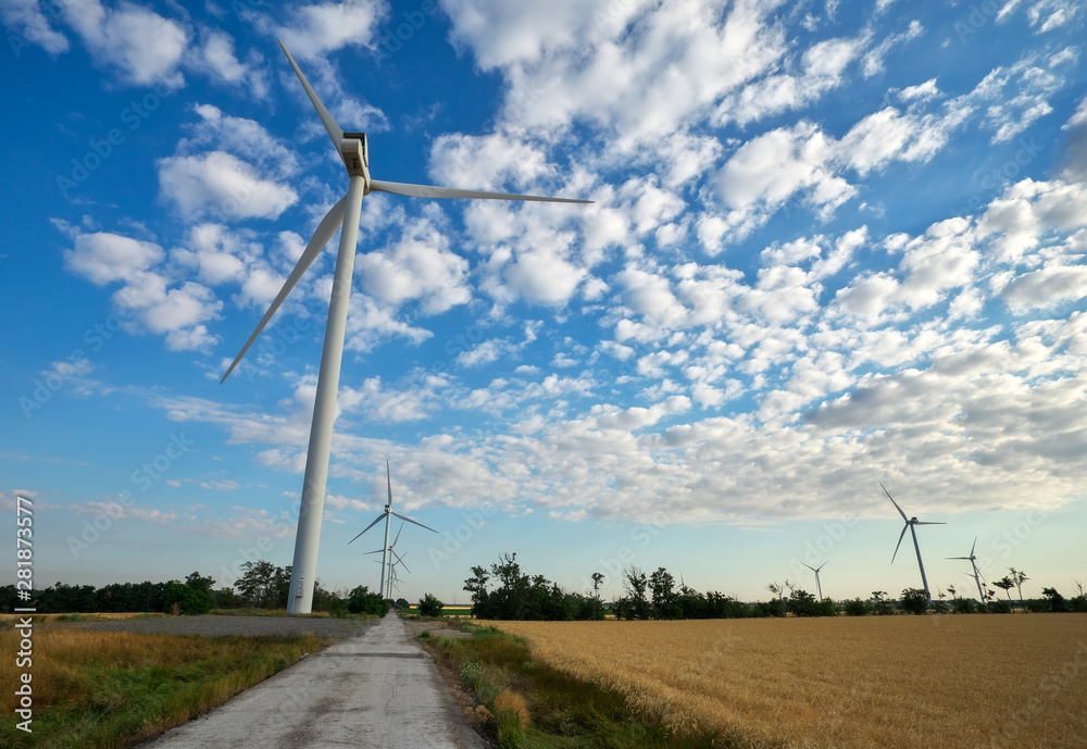 Wind turbines and agricultural field on a summer cloudy day. Energy production, clean and renewable energy. Wind turbines and agricultural field on a summer cloudy day. Energy production, clean and renewable energy.