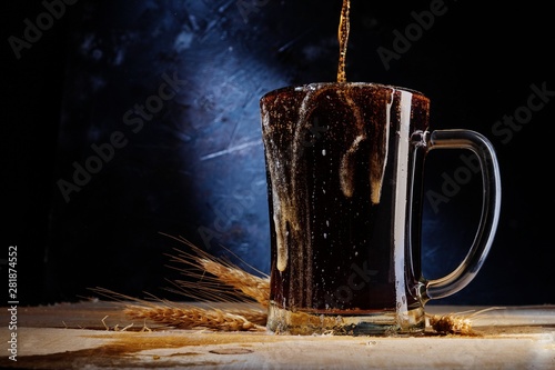 close up of beer in glass with barley on on dark background .