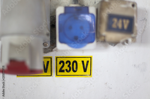 Worn out 400v, 230v and 24 industrial and multiphase power plugs and sockets on a dirty wall inside a workshop photo