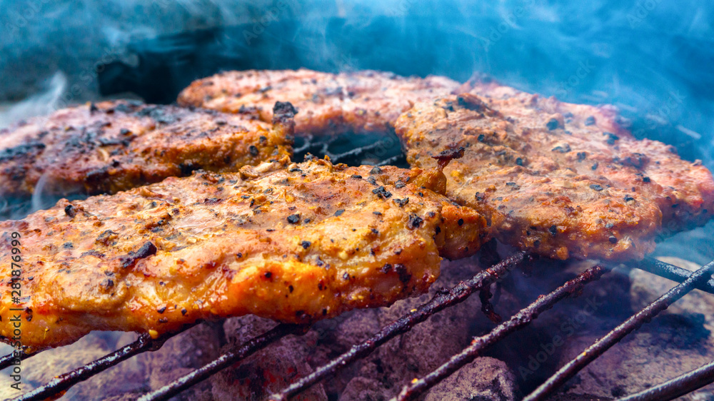 Assorted delicious grilled meat on a barbecue . Selective focus of juicy tasty steaks grilling on barbecue grill grade with flame . 