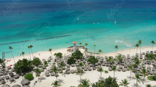 Gorgeous tropical beach with white sand against the backdrop of the turquoise sea. Landscape of a beautiful sea beach, aerial view. Beach umbrellas made of palm leaves on white sand.