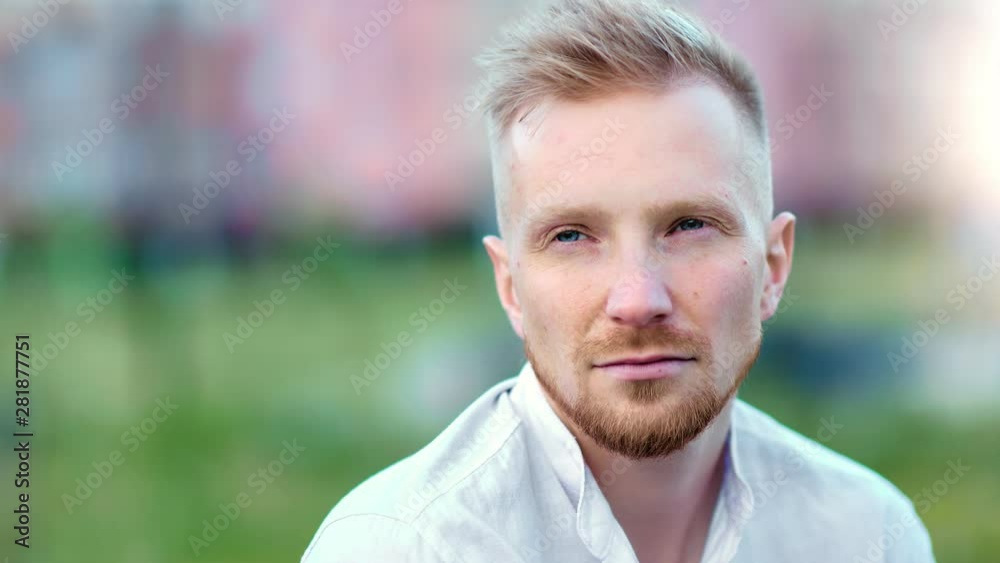 Pensive calmness young European bearded guy thinking relaxing at summer park outdoor close-up