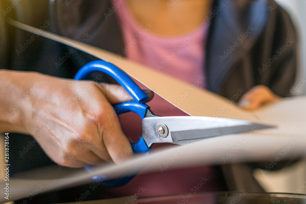 Close Up Of Hand Holding Scissors And Cutting Through Paper Stock