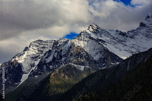 Epic snow mountains  snow covered mountain range - Daocheng Yading Nature Reserve. Ganzi  Garze  Kham Tibetan area of Sichuan Province China. Dramatic lighting during sunset  Clouds and Sky