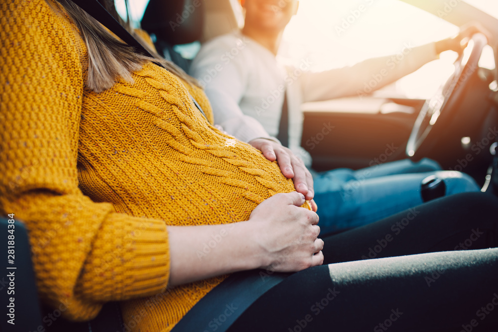 Husband and his pregnant wife driving in car.