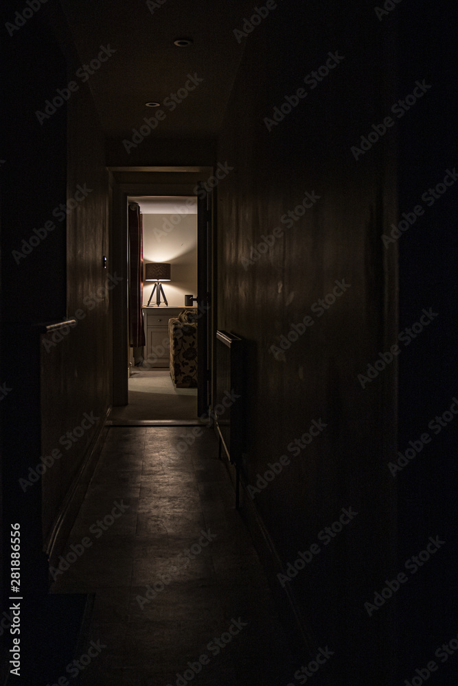 Dark corridor with warm lit room 