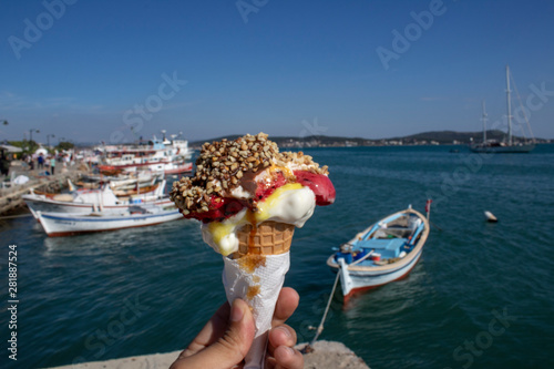 Hand holding ice cream. Sea and sky and boats in background