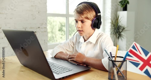 Teenage boy in headphones studying english online, watching video courses, modern education technologies photo
