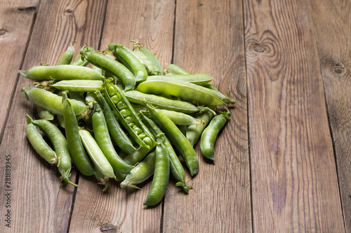 Young fresh green peas in a pod on a wooden table.