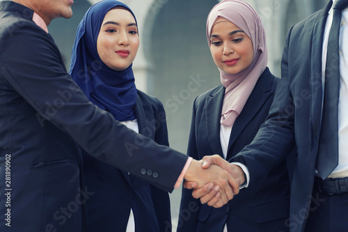 Muslim Asian business people shaking hands with new partner, business co-working teamwork concept. Successfull entrepreneur over a blur majestic building photo