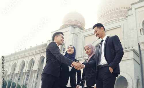 Muslim Asian business people shaking hands with new partner, business co-working teamwork concept. Successfull entrepreneur over a blur majestic building