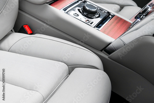 Modern luxury car white leather interior with natural wood panel. Part of leather car seat details with stitching. Interior of prestige modern car. White perforated leather. Car detailing. Car inside © Aleksei