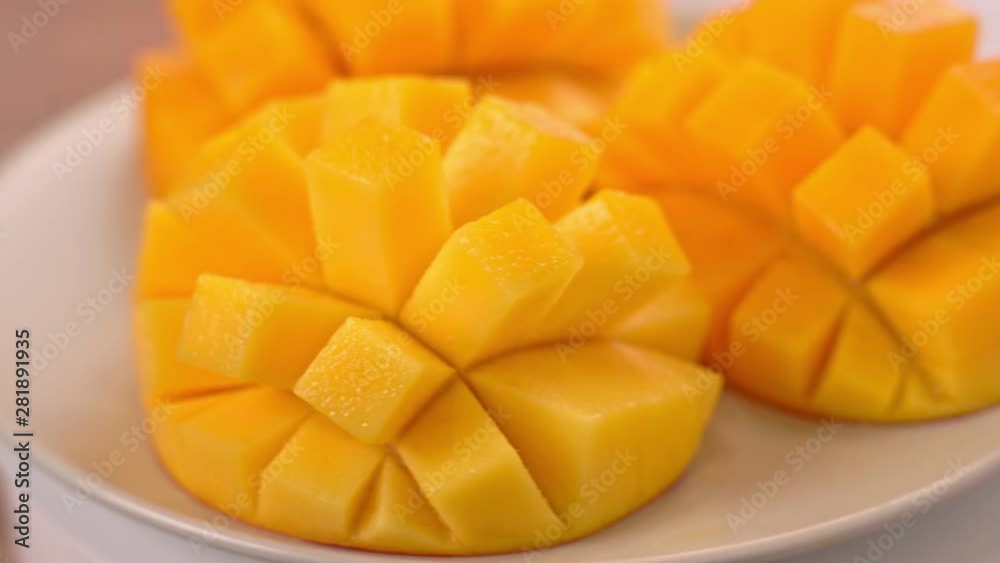 Beautiful fresh chopped mango, showing on a rotating white plate, close up, 4K video shot.