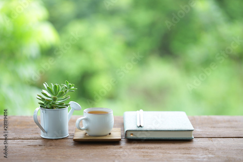tea cup and small plant pot and diary notebook on wooden table