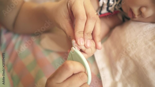 mother nail cutting her baby girl's nail while the baby sleeping