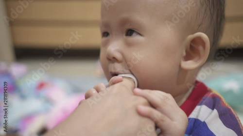 mother use gauze cleaning her baby girl's tongue