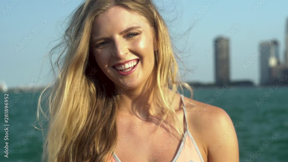 Beautiful Caucasian blonde female with green/blue eyes looks directly into the camera seductively then laughs happily as the wind blows her hair. the Chicago rivers flows towards the tourist city Beautiful Caucasian blonde female with green/blue eyes looks directly into the camera seductively then laughs happily as the wind blows her hair. the Chicago rivers flows towards the tourist city
