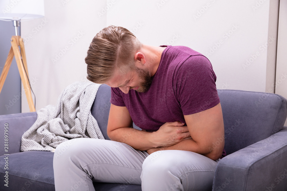 Man Having Stomach Pain Sitting On Sofa