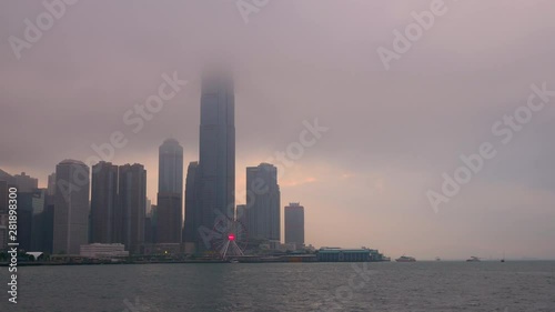 Time lapse of Hong Kong cityscape with sun light in the hard mist at the harbor in the raining day