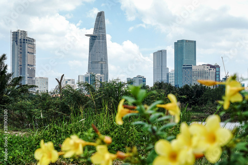 A different view of Ho Chi Minh City, Vietnam's modern skyline with green jungle landscape and flowers next to skyscrapers and high rise buildings