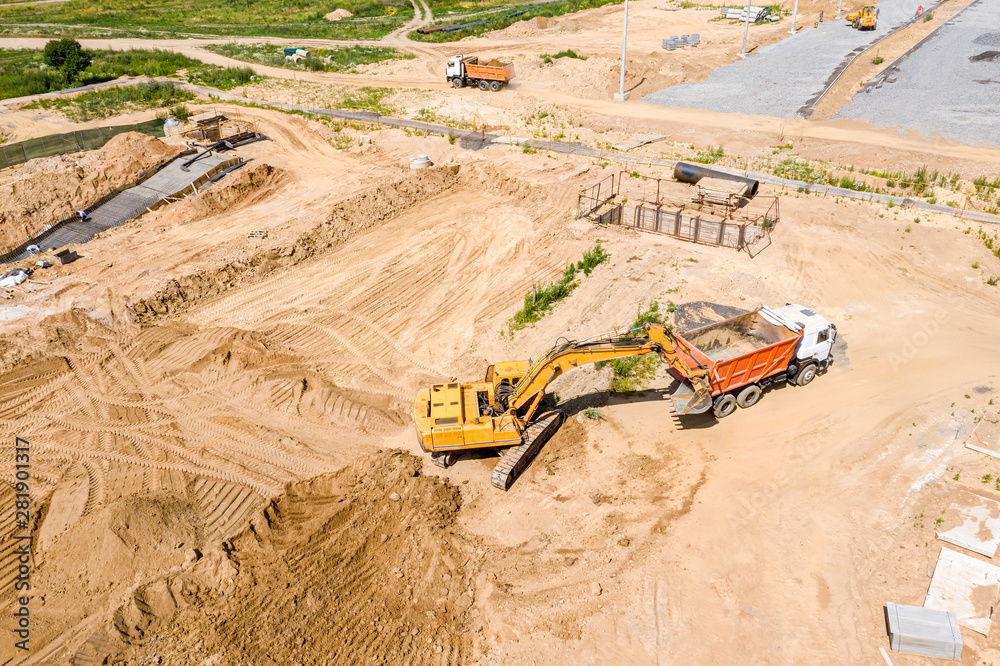 top view of yellow excavator loading ground in dump truck at construction site top view of yellow excavator loading ground in dump truck at construction site