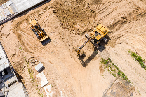 aerial top view of yellow industrial heavy machines moving ground at construction site