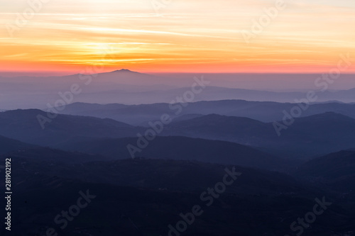 Beautifully colored sky at sunset, with mountains layers and mist between them