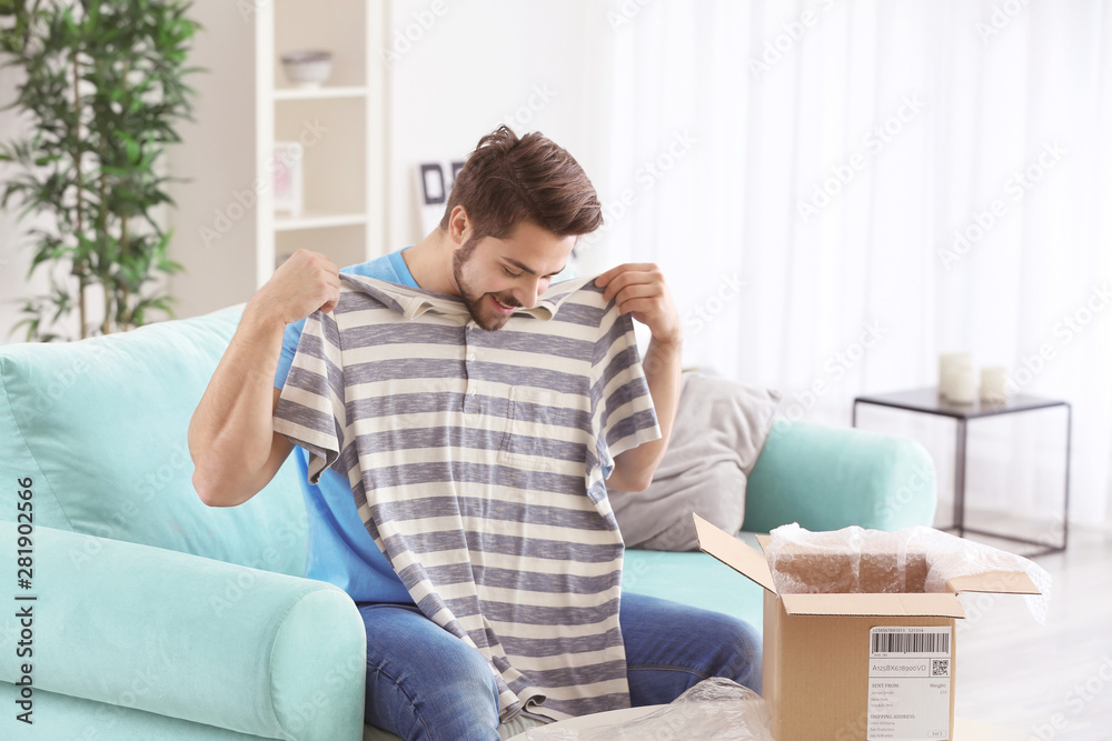 Young man unpacking parcel at home Young man unpacking parcel at home