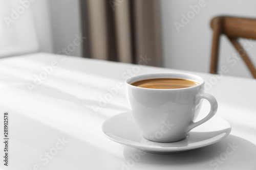 Cup of hot aromatic coffee on white table indoors. Space for text