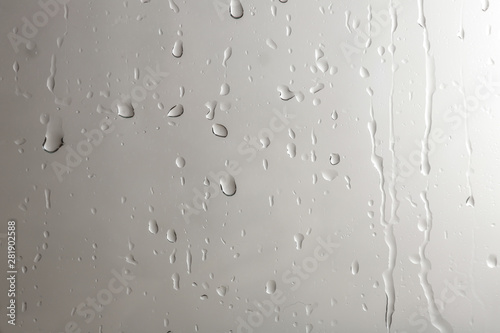 Glass with rain drops against light background