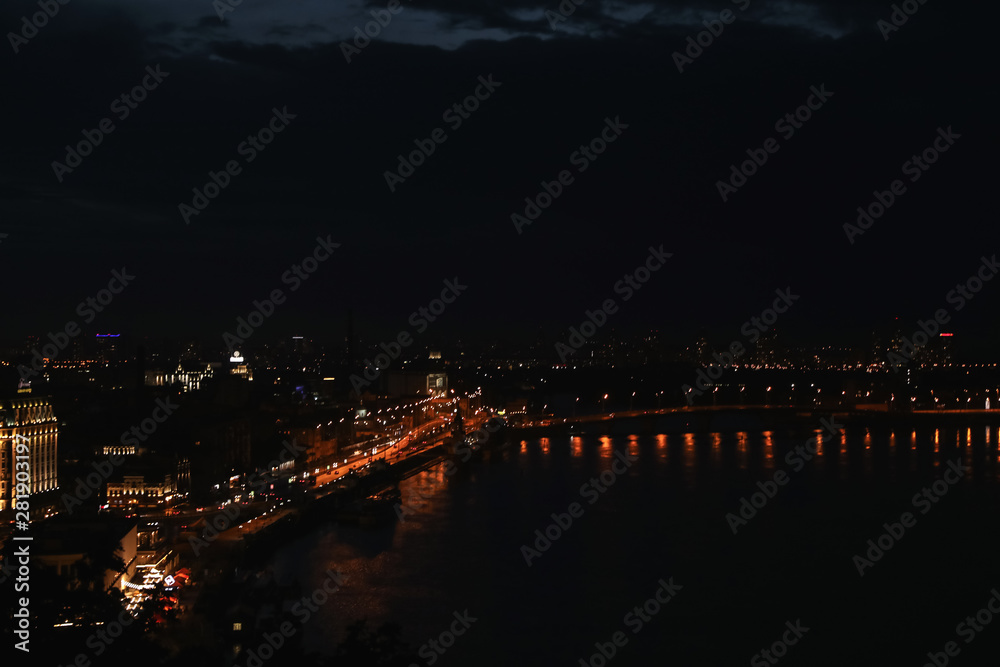KYIV, UKRAINE - MAY 21, 2019: Beautiful view of night cityscape with illuminated buildings near river KYIV, UKRAINE - MAY 21, 2019: Beautiful view of night cityscape with illuminated buildings near river